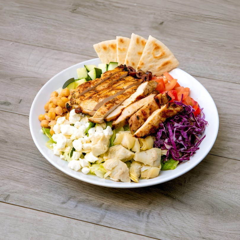 A Daphne's Greek Cafe chicken plate with pita, chickpeas, feta, artichokes, and vegetables.