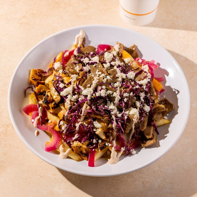 Daphne's Greek Cafe's gyro fries topped with meat, feta, red cabbage, and pickled onions.